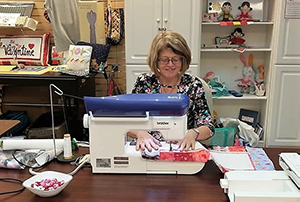 president of ASG sitting at sewing machine sewing